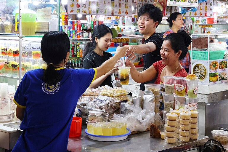 Händler und Kunden an einem Verkaufsstand im Ben-Thanh-Markt, Saigon