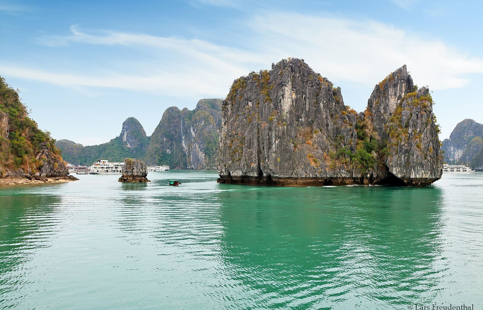 Smaragdgrünes Wasser, Ausflugsboote und steil in den Himmel ragende Inseln in der Halong-Bucht Vietnams