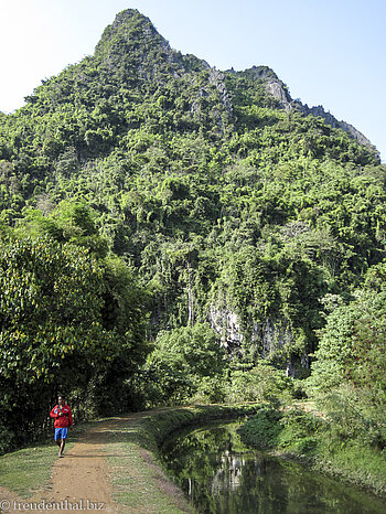 Spaziergang entlang einem Wasserlauf bei den Karstfelsen von Vang Vieng