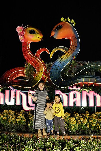 Mutter mit Kind lassen sich vor zwei Glücksdrachen in Hué fotografieren.
