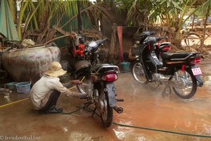 Motorradpflege in Kambodscha inmitten von rotem Schlamm