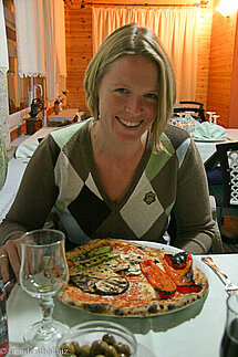 Annette freut sich über ihre große Pizza.