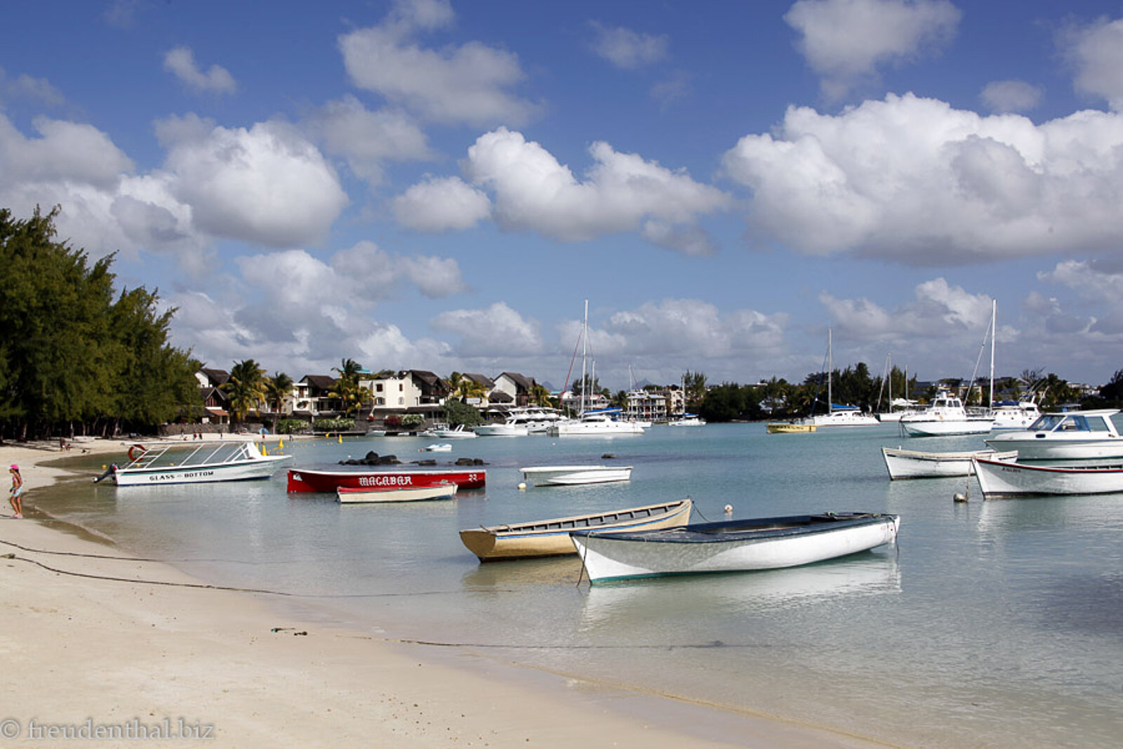 Blick über den Strand und zu mehreren im Wasser dümpelten Booten an der Grand Baie von Mauritius