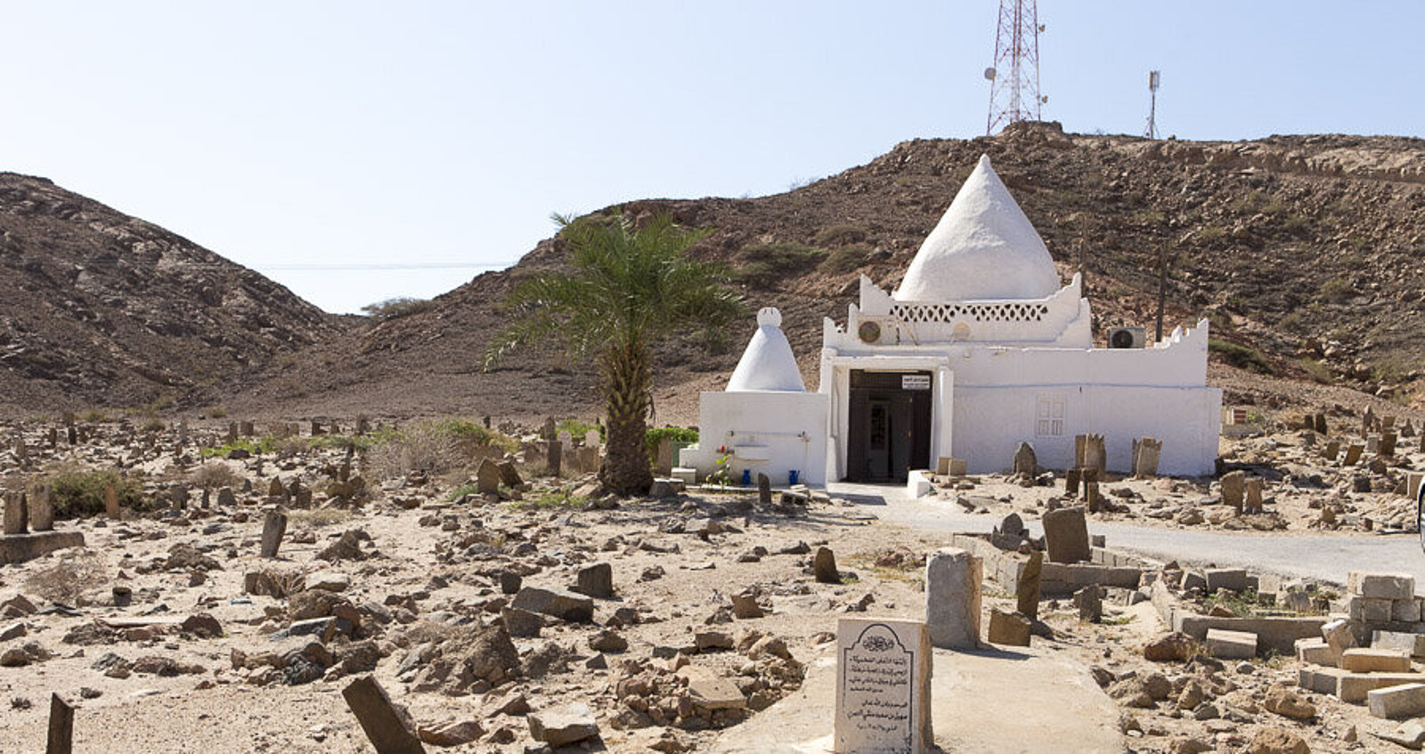 Blick über einen alten Friedhof zum Mausoleum von Mohammed bin Ali al Alawi nahe Mirbat im Oman