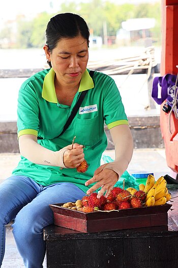 Vietnamesin beim Vorbereiten von Rambutans, einer mit der Litschi verwandten Frucht