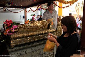 Blattgoldkleben an einer Buddha-Statue in Bangkok