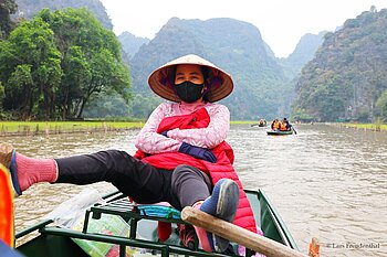 im Tam Cốc-Tal rudern Frauen die Boote mit den Beinen über den Fluss Ngoạ Đồng