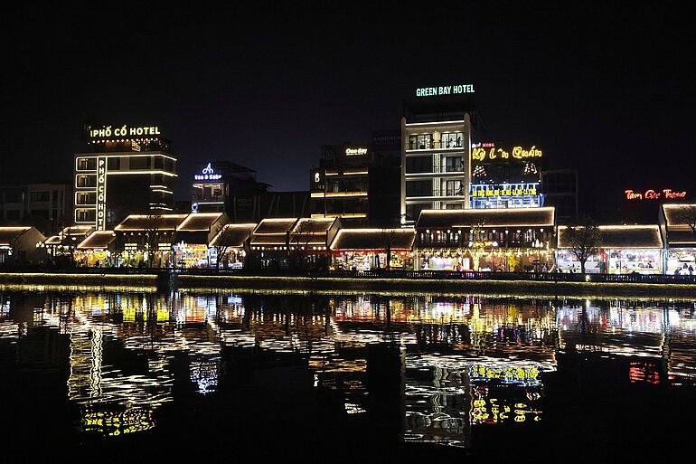 Die Flaniermeile von Hoa Lư spiegelt sich bei Nacht in einem Kanal.