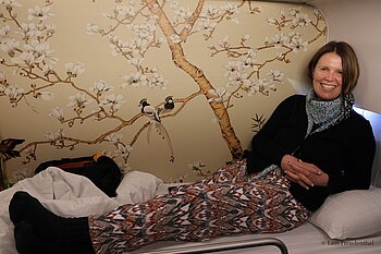 Annette vor einer Tapete mit Magnolien und Paradiesbandschnäppern 