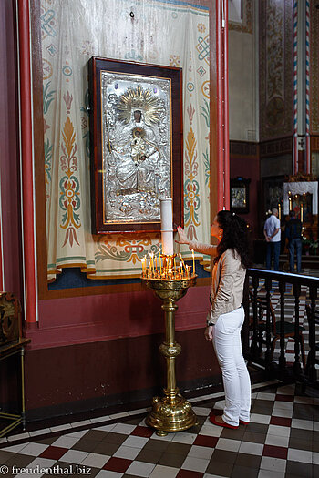 Eine Frau hält ihre Hand über Kerzen in der Kathedrale von Tallinn.